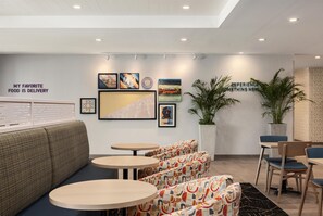 A modern interior with seating, artwork, and a sign reading 'MY FAVORITE FOOD IS DELIVERY.'