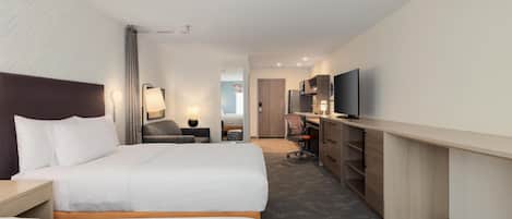 A hotel room with two beds, a desk, a chair, a TV, and a mirror.