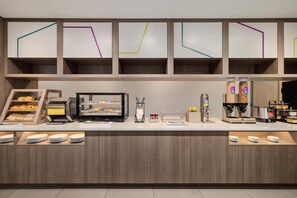 A breakfast bar with a bread and bagel station, a coffee machine, and a cereal dispenser.