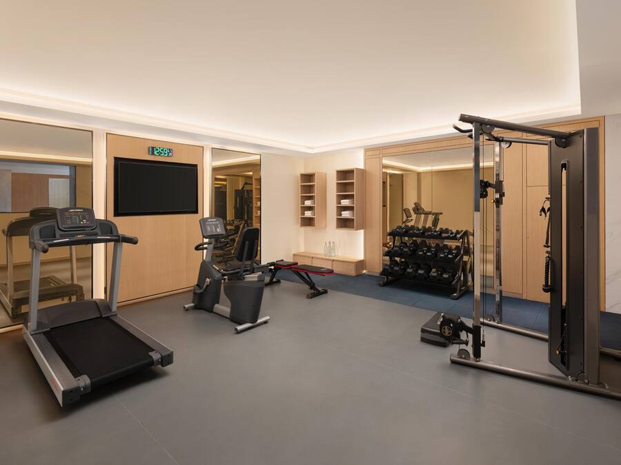 Un gimnasio moderno con cinta de correr, elíptica y máquinas de pesas.