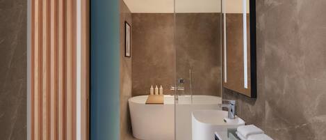 A modern bathroom with a freestanding bathtub, a glass shower enclosure, and a vanity with a mirror.