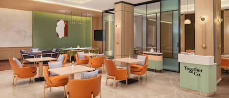 A modern hotel lobby with seating areas, a reception desk, and a large wall with a map.
