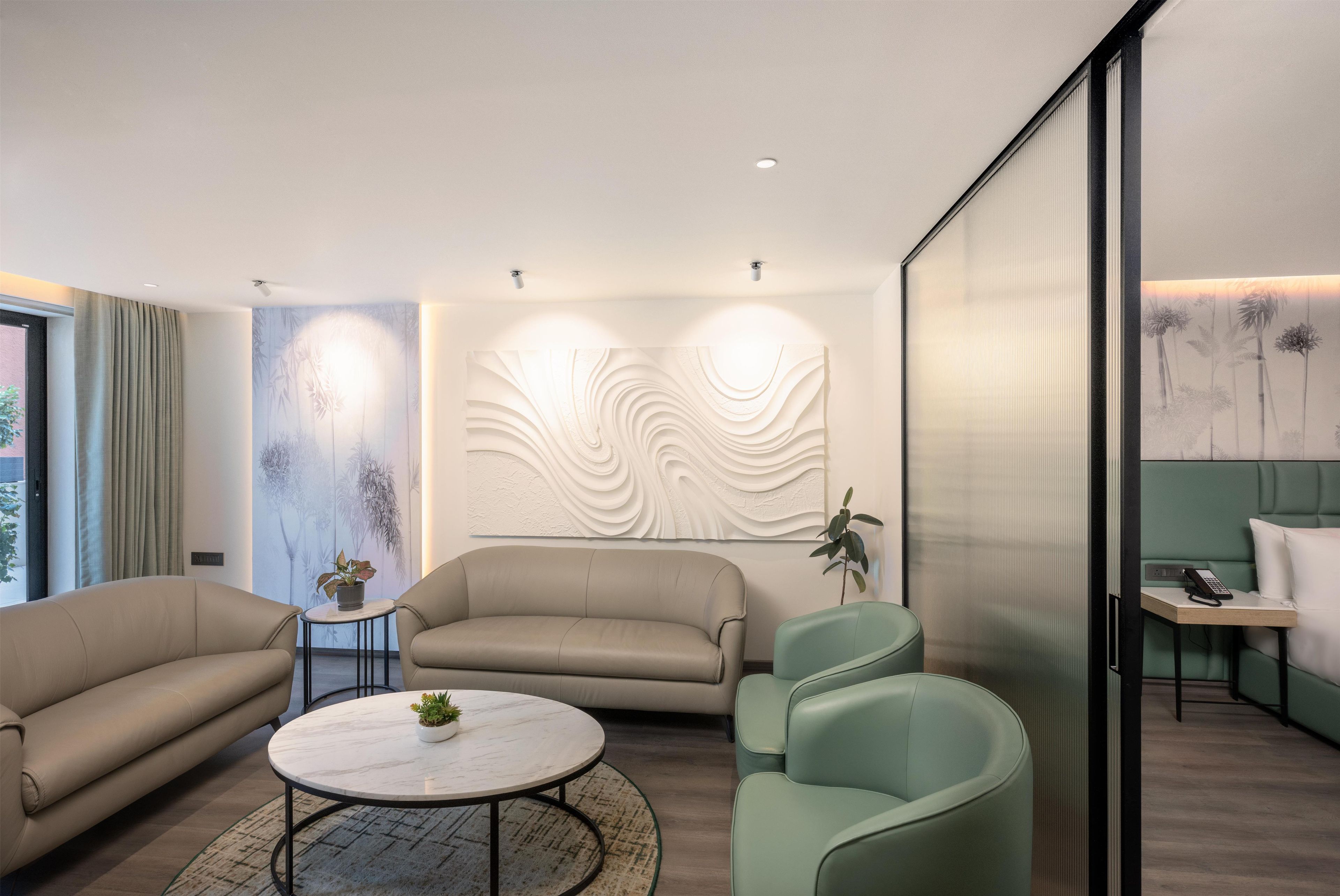 Un salon moderne comprenant un canapé, des fauteuils, une table basse et un mur décoratif.