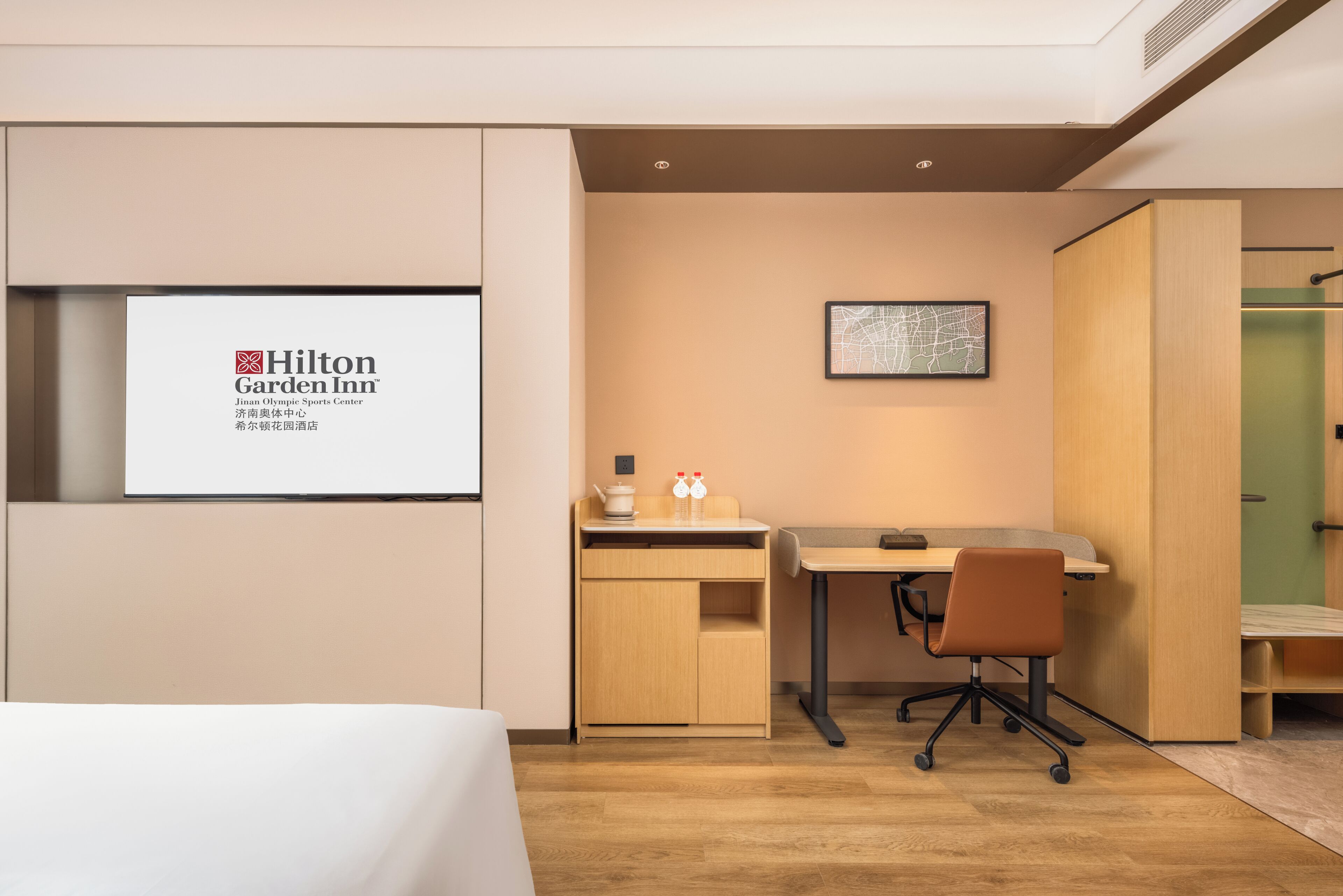 Una habitación de hotel moderna con una cama, un escritorio, una silla y un minibar.