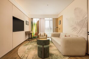 Suite – deluxe, 1 kingsize-seng | Oppholdsområde | En 65-tommers TV med kabel-kanaler