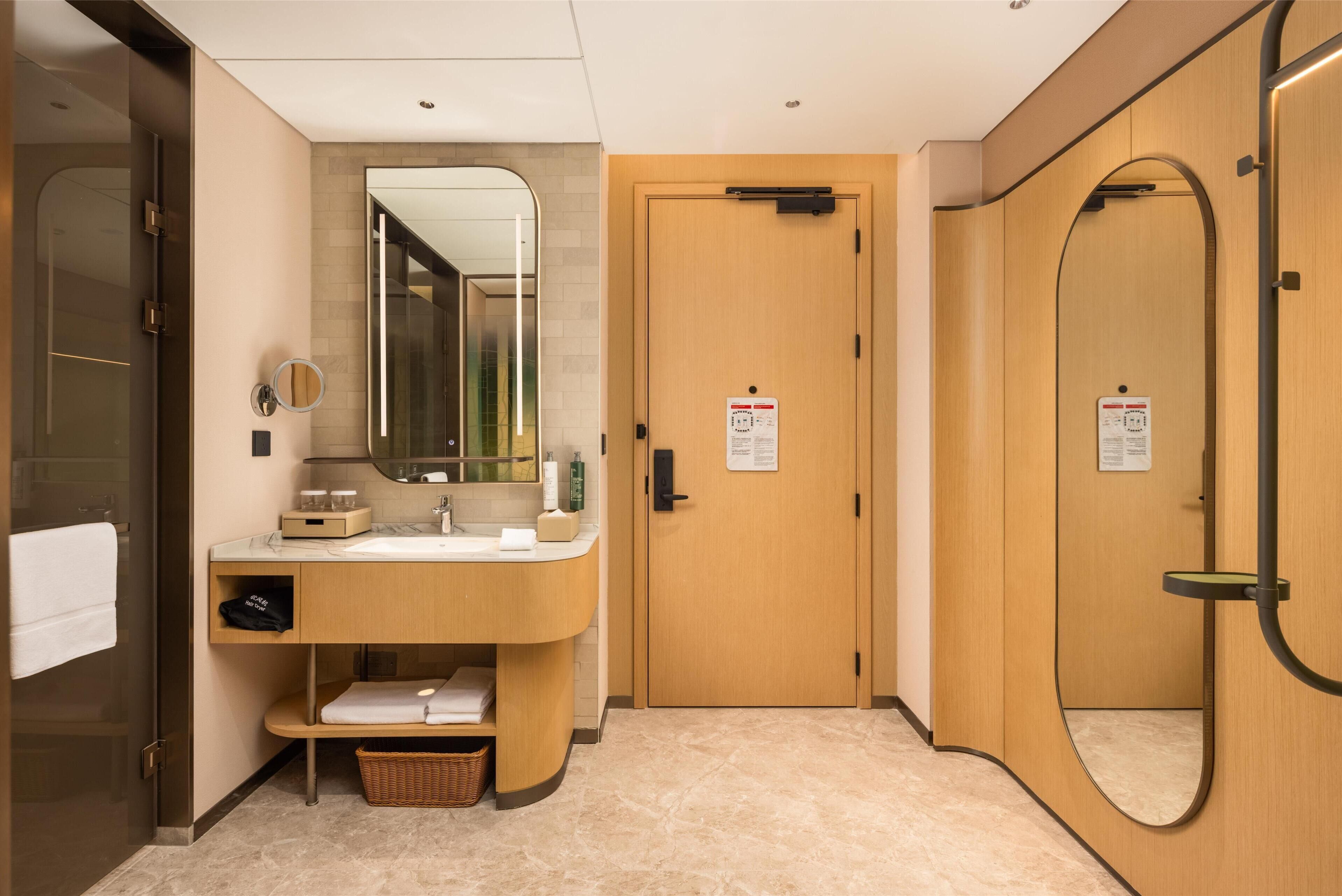 A modern bathroom with a vanity, mirror, and a wooden door.