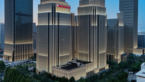 Un edificio moderno de gran altura con un diseño vertical distintivo y un letrero destacado en la parte superior.