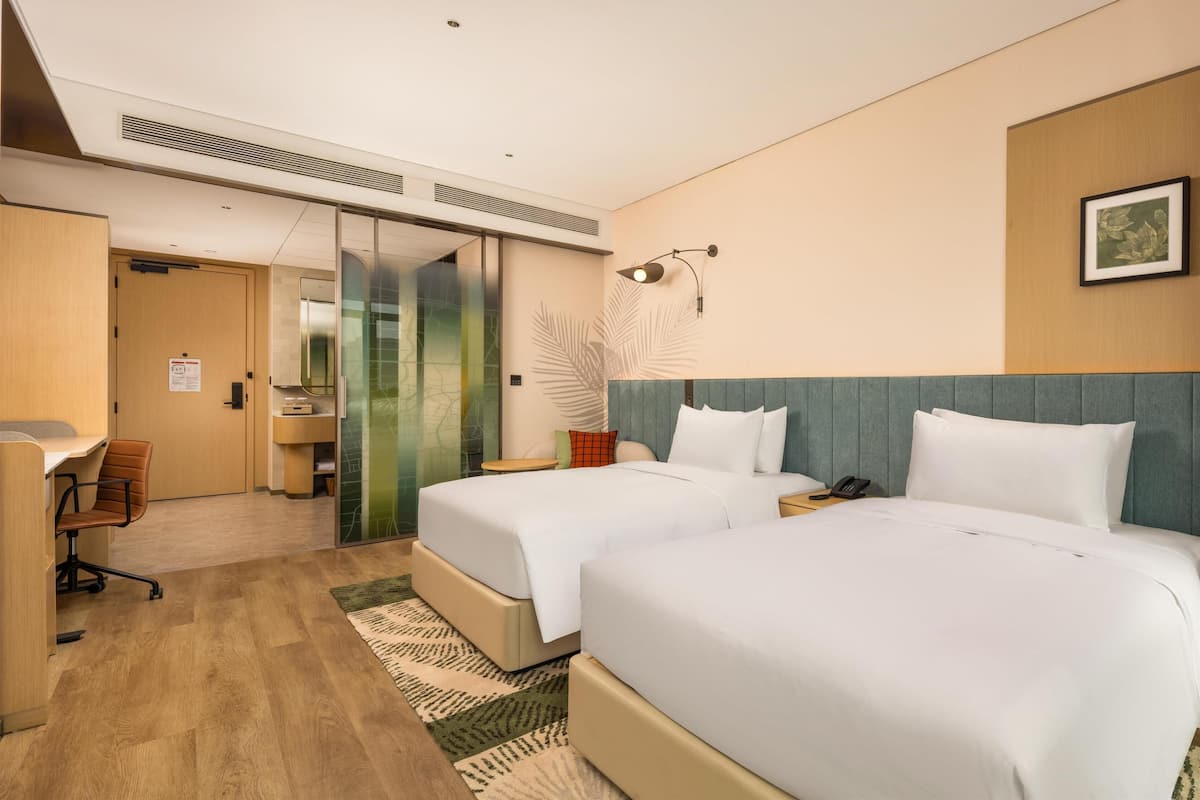 Habitación de hotel con dos camas, un escritorio y una silla.