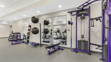 A gym with exercise equipment, mirrors, and a weight rack.