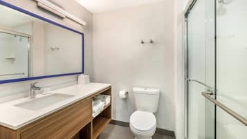 Une salle de bain moderne avec une douche à parois de verre, des toilettes blanches et un meuble-lavabo en bois avec un miroir.