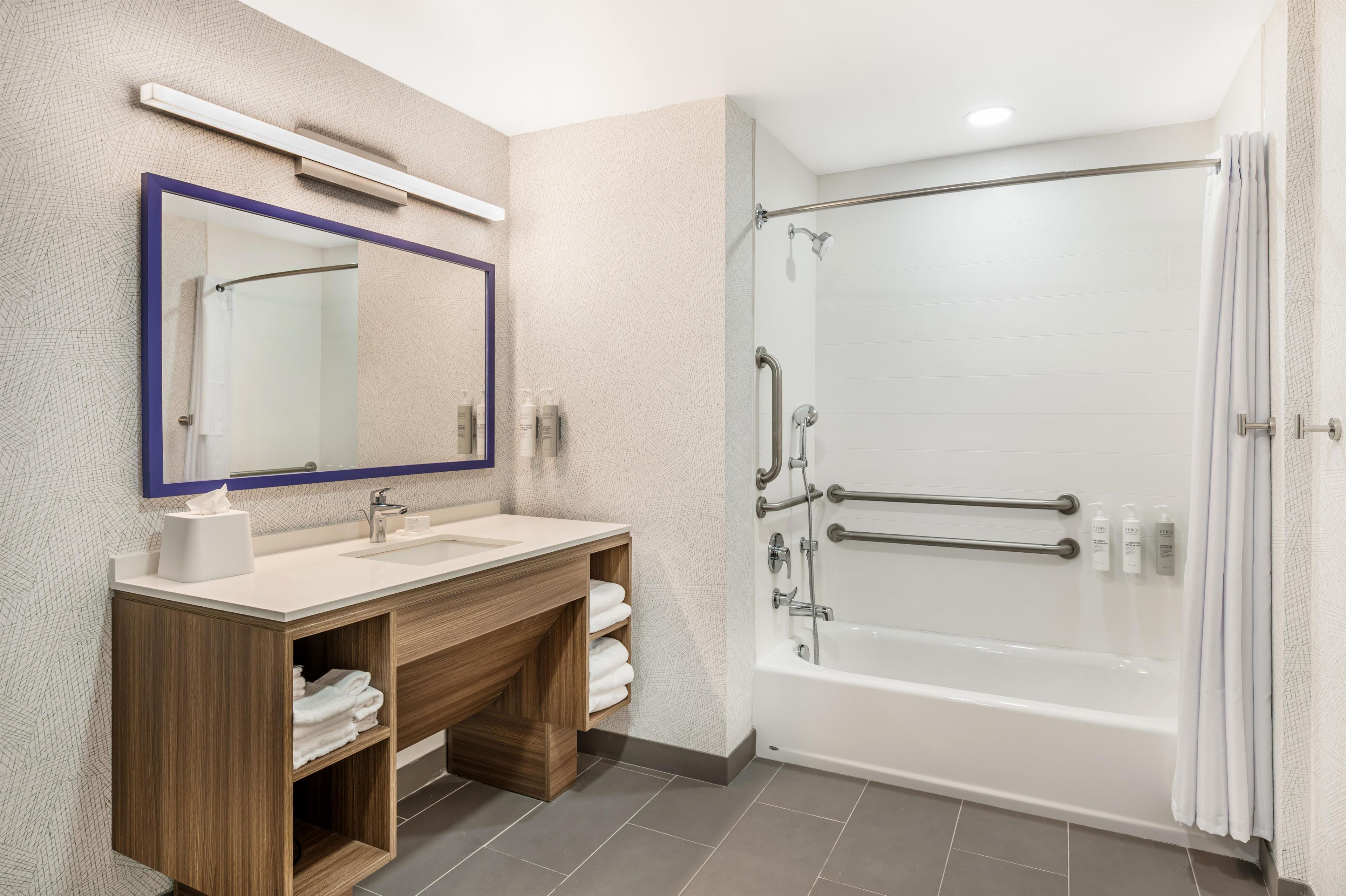 Un baño moderno con tocador de madera, un espejo grande, cabina de ducha con mampara de vidrio y una bañera.