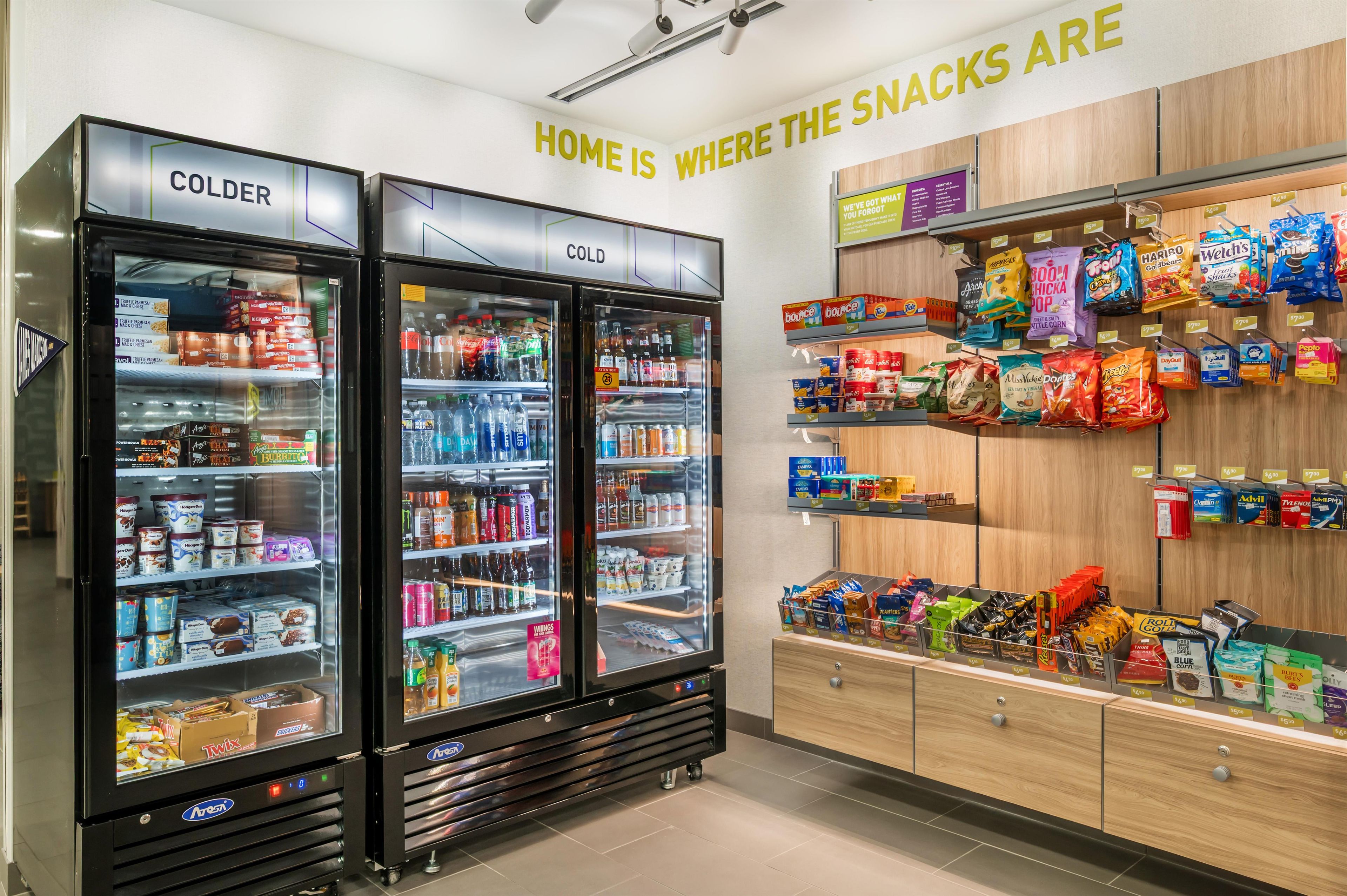 A store with two refrigerators labeled 'COLDER' and 'COLD,' and shelves stocked with snacks.