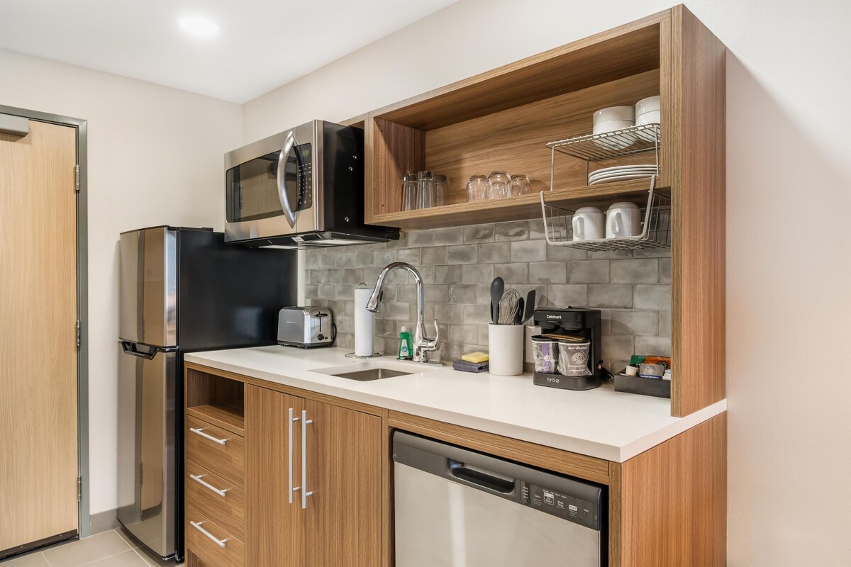 A compact kitchen with a microwave, toaster, sink, and dishwasher.