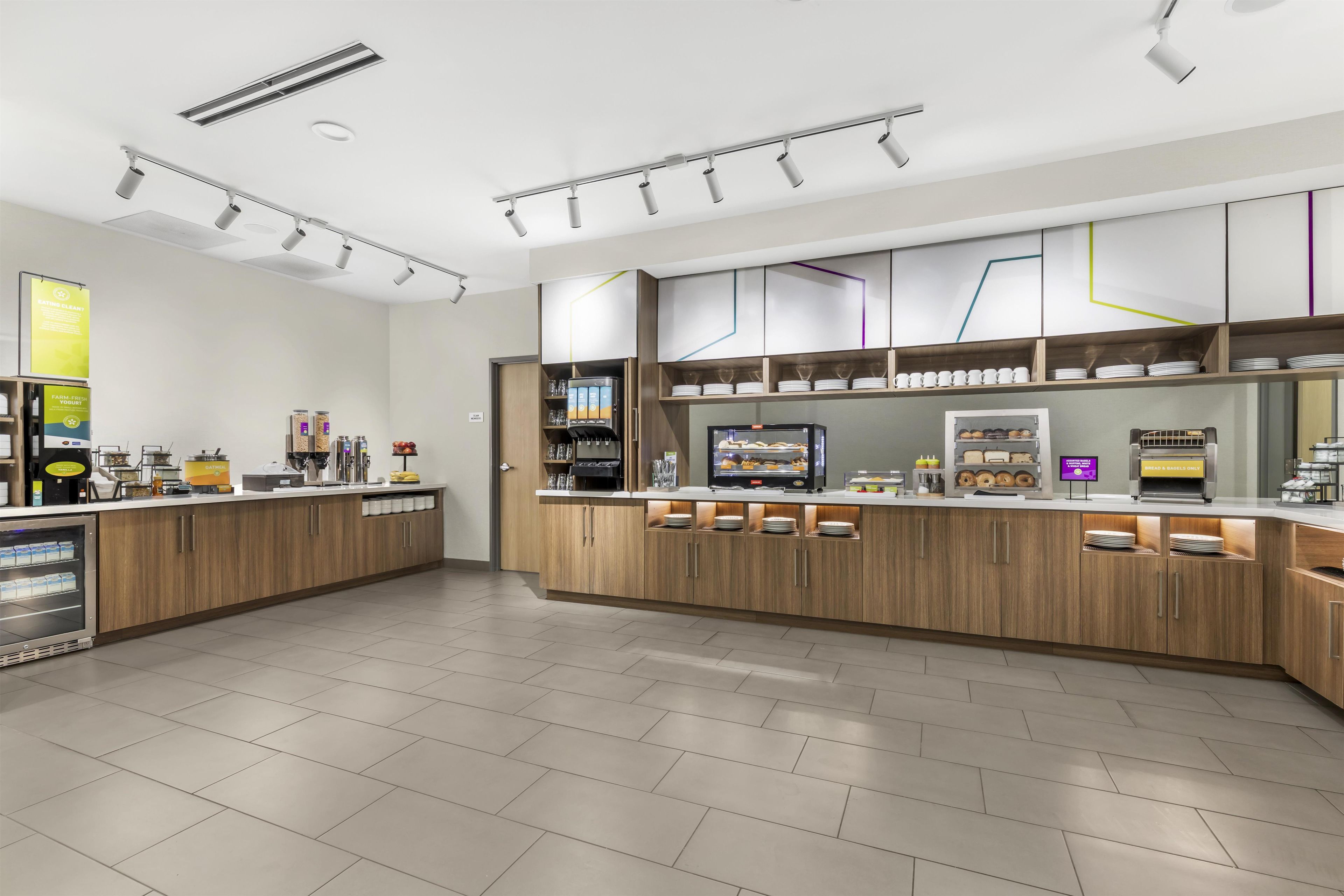 A modern kitchen with wooden cabinets, a built-in coffee machine, and a display of food items.
