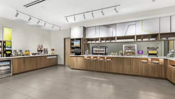 A modern kitchen with wooden cabinets, a built-in coffee machine, and a display of food items.