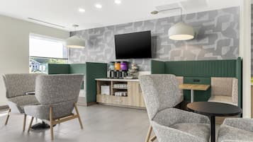 Un interior moderno con asientos, un televisor de pantalla plana y una zona de café.