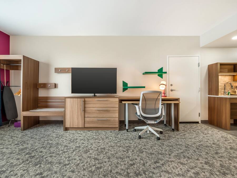 Un dormitorio moderno con una cama, una mesita de noche y un escritorio con silla.