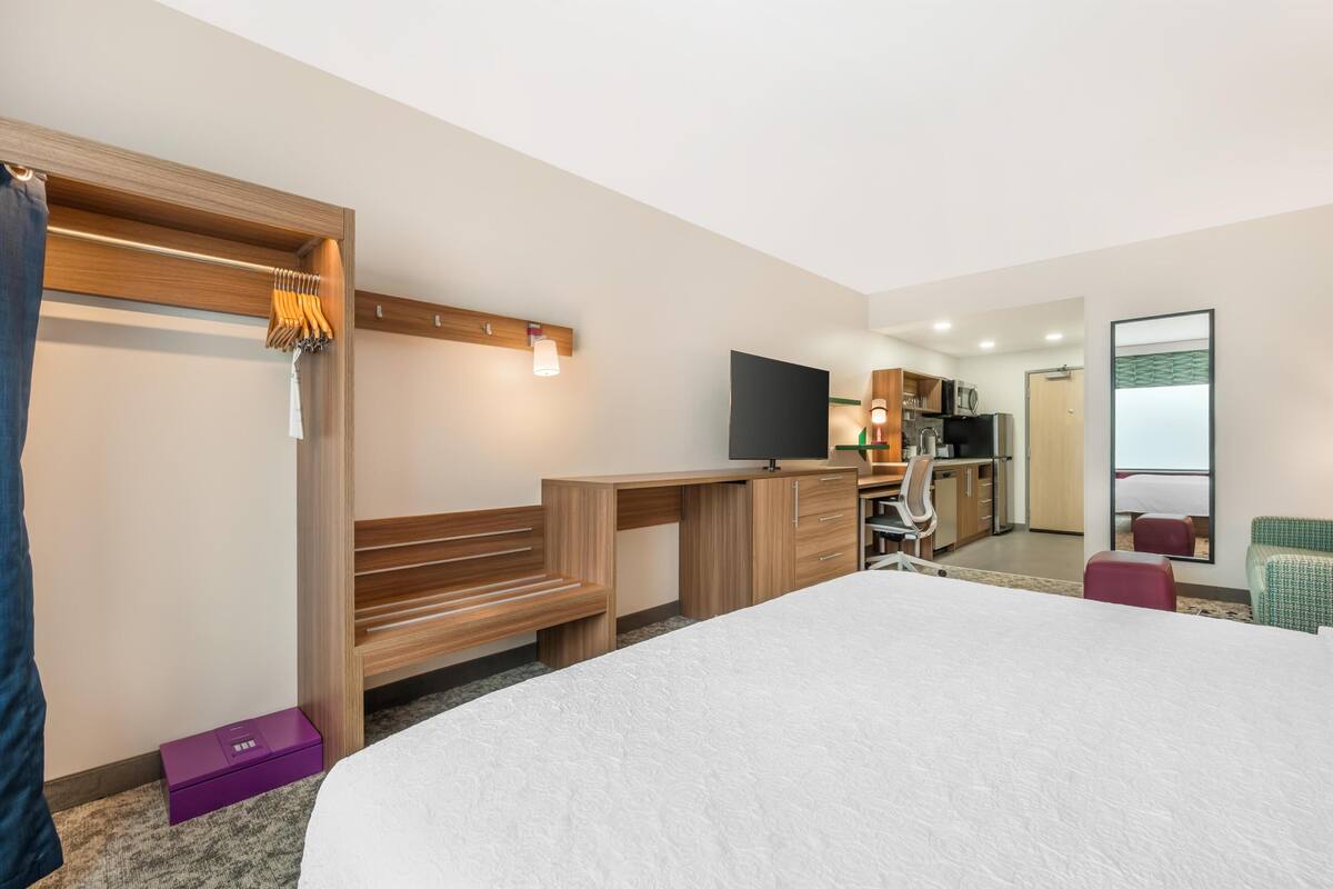 Hotelkamer met een bed, bureau, televisie, kitchenette en badkamer.