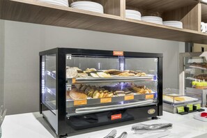 A self-service breakfast station with various food items and a caution hot sign. - Home2 Suites By Hilton Harrisonburg University (Harrisonburg)