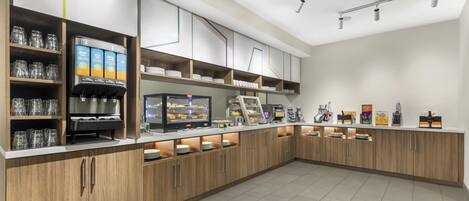 Een modern café met een bedieningsluik, koffieautomaten en diverse eetgelegenheden.