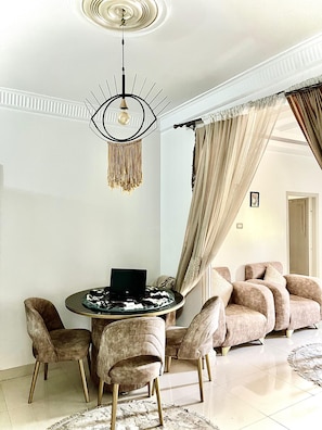 A modern living room with a round coffee table, a laptop, and a chandelier. There are plush chairs and a sofa with curtains. - condo in beautiful Aswan Governorate with WiFi, AC (Aswan Governorate)