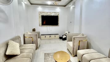 Uma sala de estar moderna com sofás, uma mesa de centro, uma televisão e um ventilador de teto.