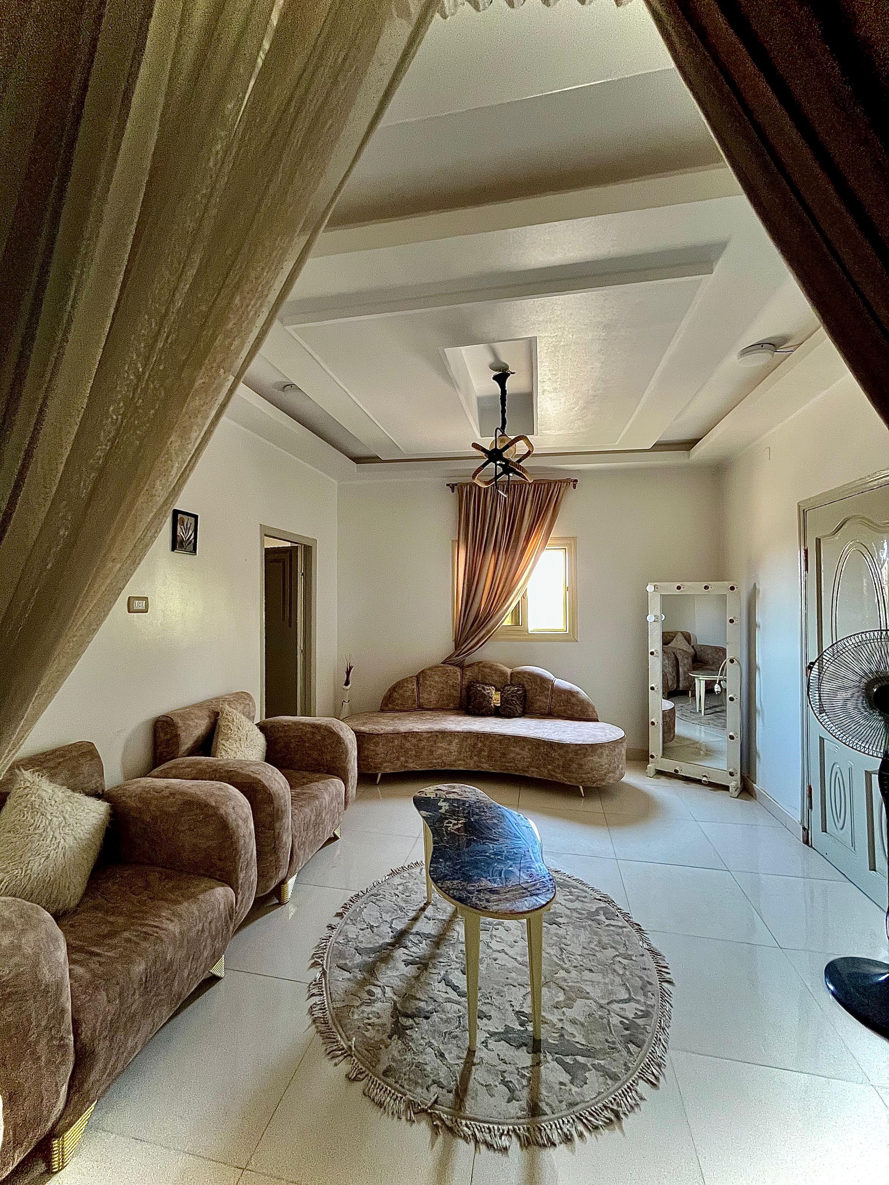Ein Wohnzimmer mit einer gebogenen Couch, einem runden Couchtisch und einem beleuchteten Spiegel.