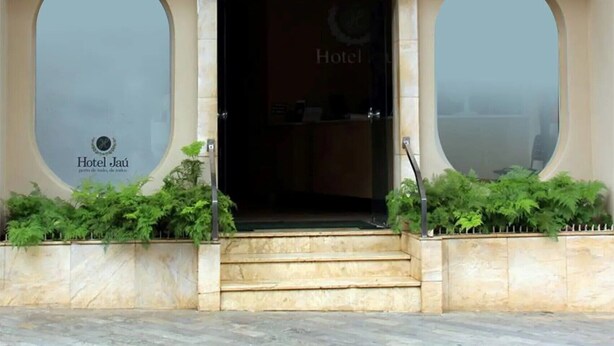 The entrance to Hotel Jaú with a prominent sign above the door and two large arched windows on either side. - Hotel Jaú (Jau)