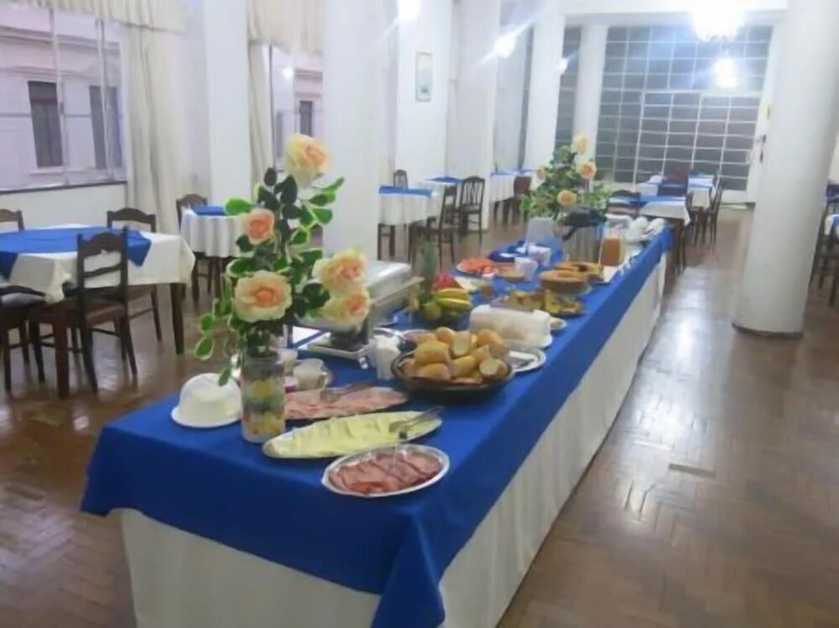 Una larga mesa de comedor con mantel azul, decorada con flores y diferentes alimentos.