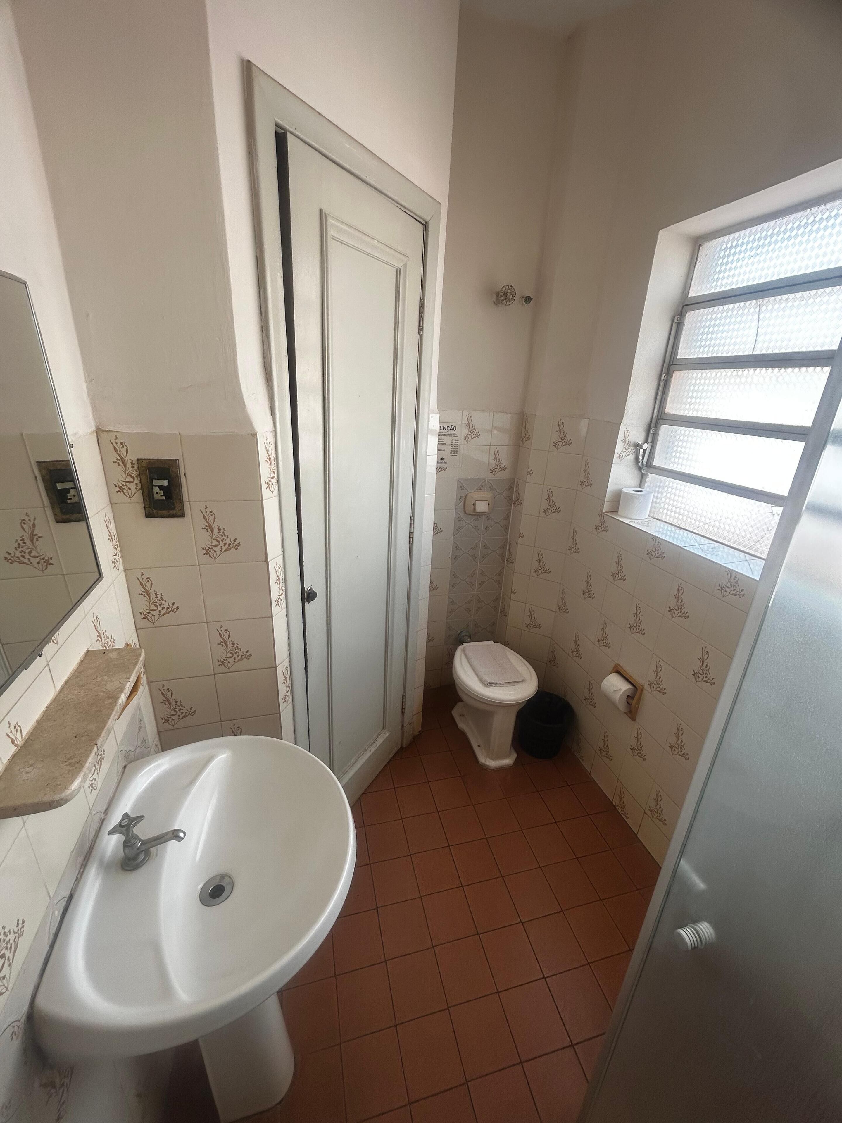Un baño pequeño con lavamanos, inodoro y ventana.