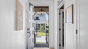 A hallway leading to a residential entrance with a view of a house and parked cars. - Silicon Slopes Retreat (Lehi)