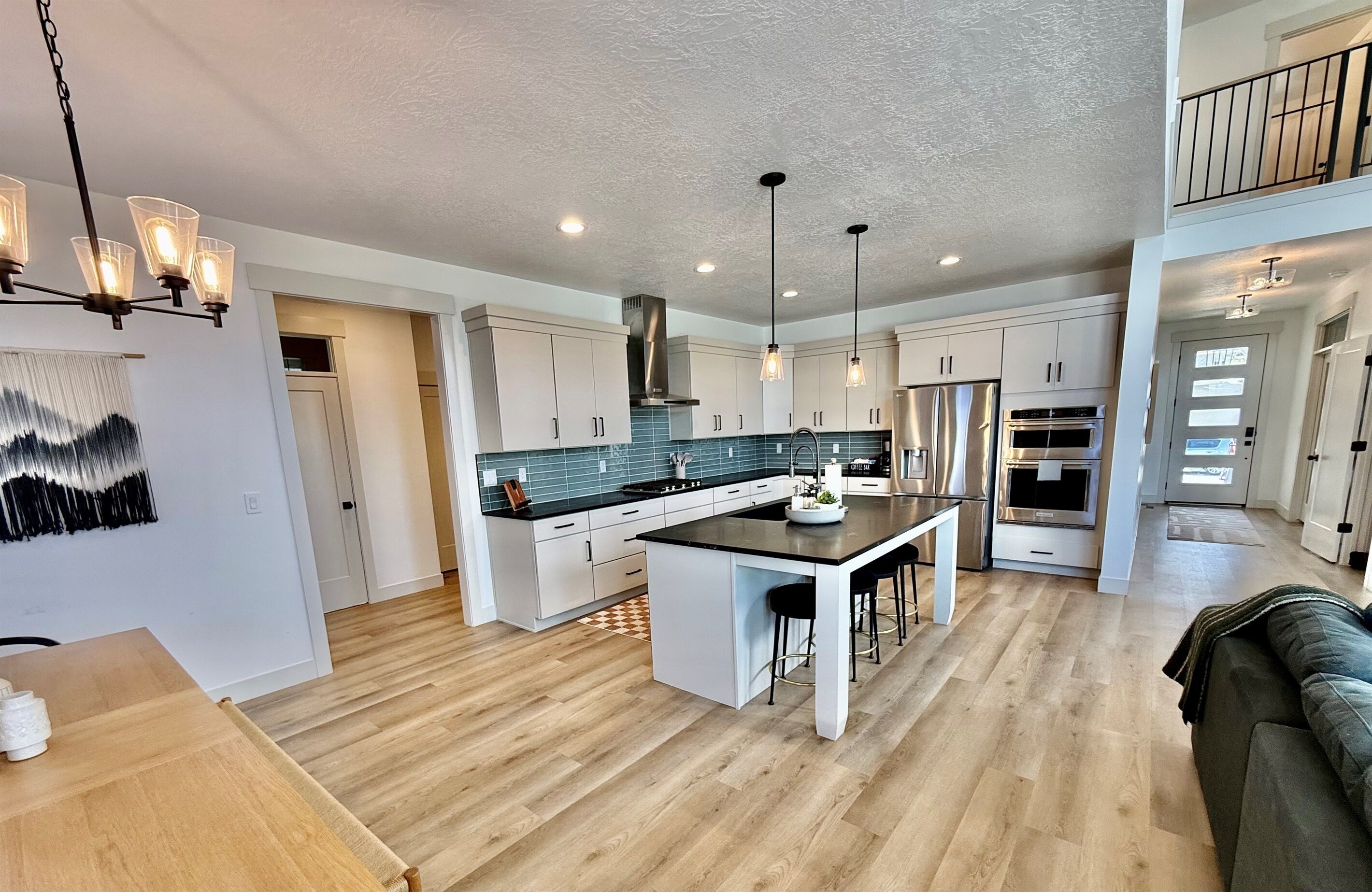 A modern kitchen with a central island, pendant lighting, and a view to the upper level.