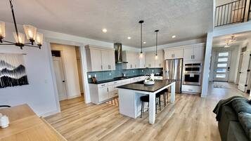 A modern kitchen with a central island, pendant lighting, and a view to the upper level.