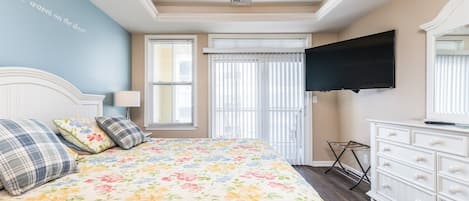 A bedroom with a bed, a dresser, a television, and a ceiling fan.