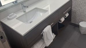 Een moderne badkamer met een grote spiegel, een wastafel, een handdoekrek en een toilet.