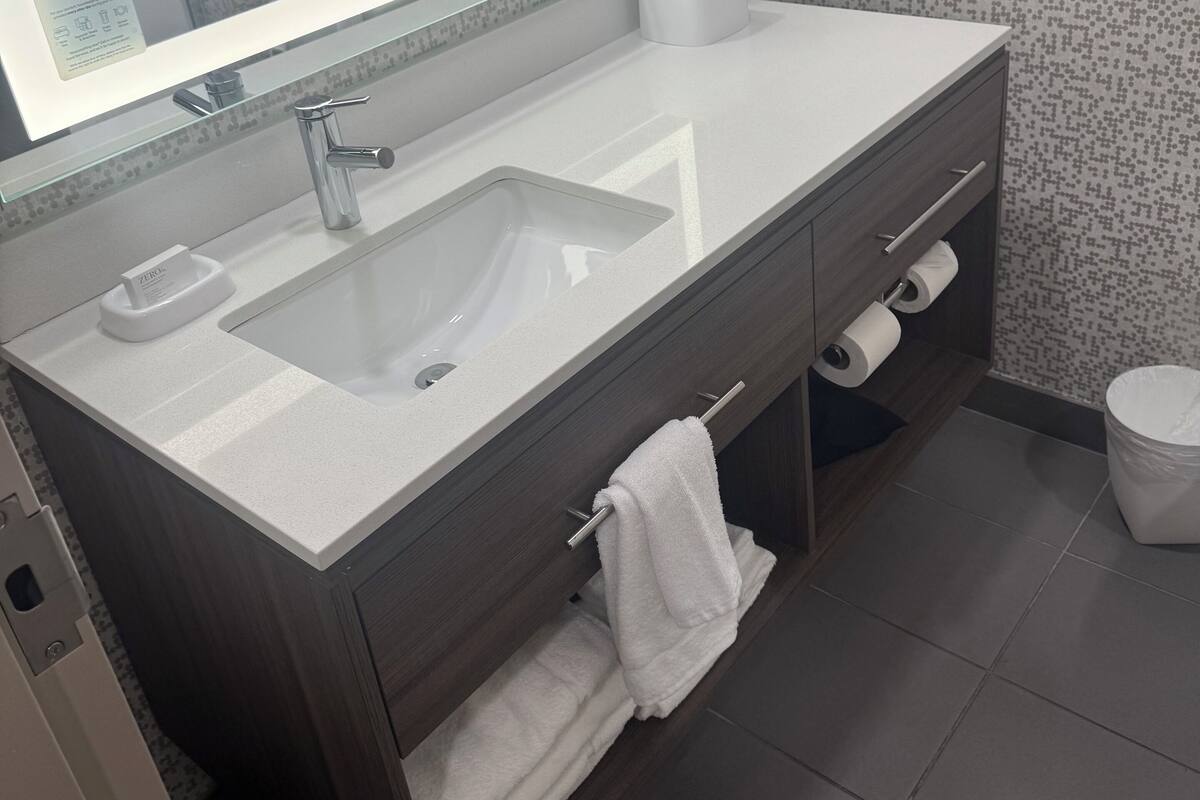 Een moderne badkamer met een grote spiegel, een wastafel, een handdoekrek en een toilet.