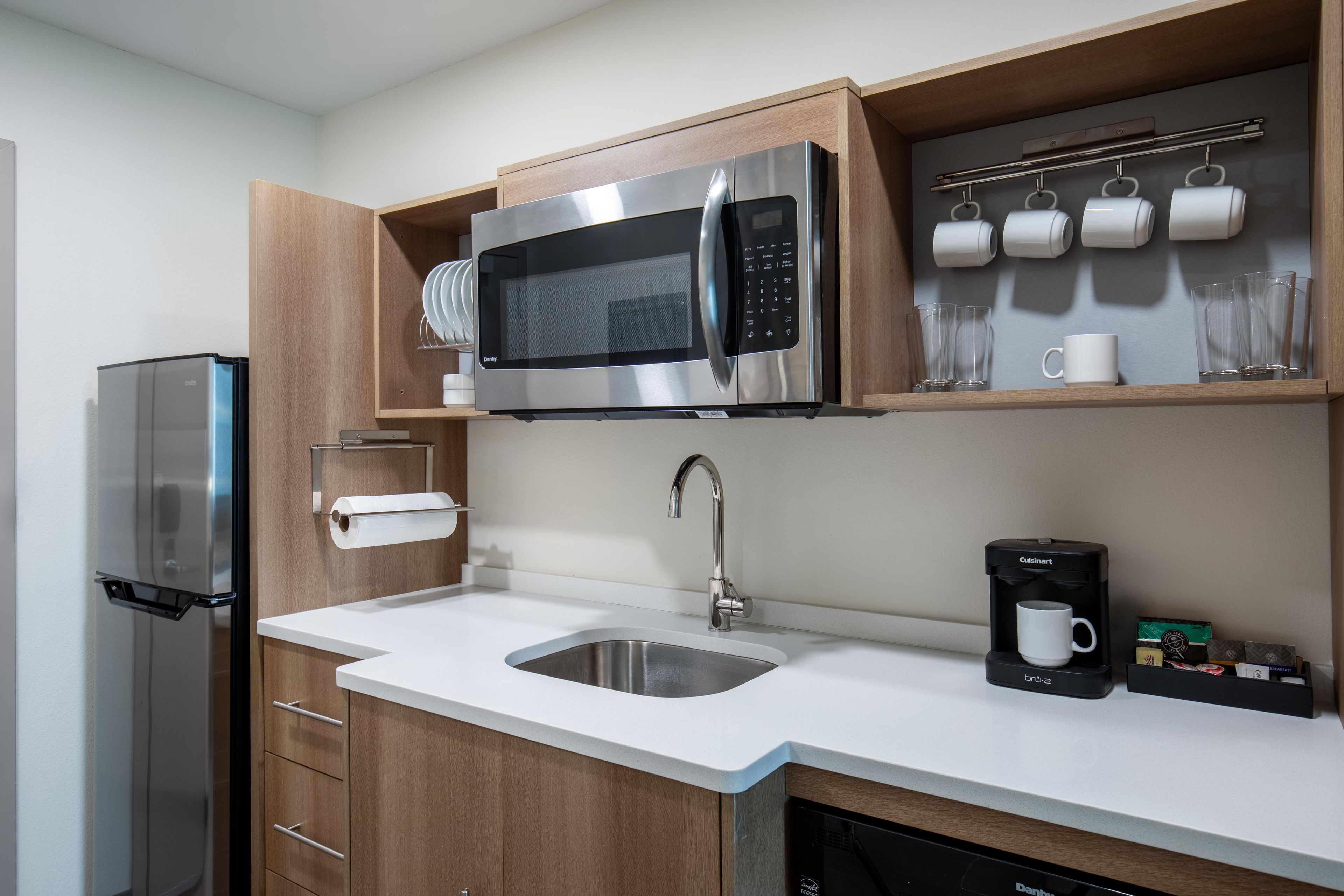 Una cocina moderna con microondas integrado, cafetera y escurreplatos.