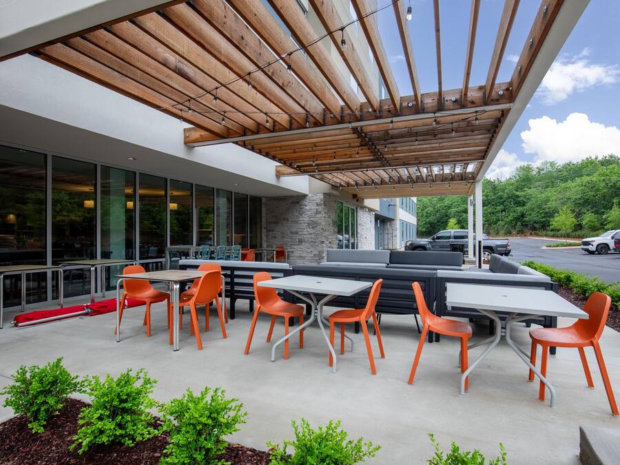 An outdoor seating area with tables and chairs, a covered patio, and a view of the street.