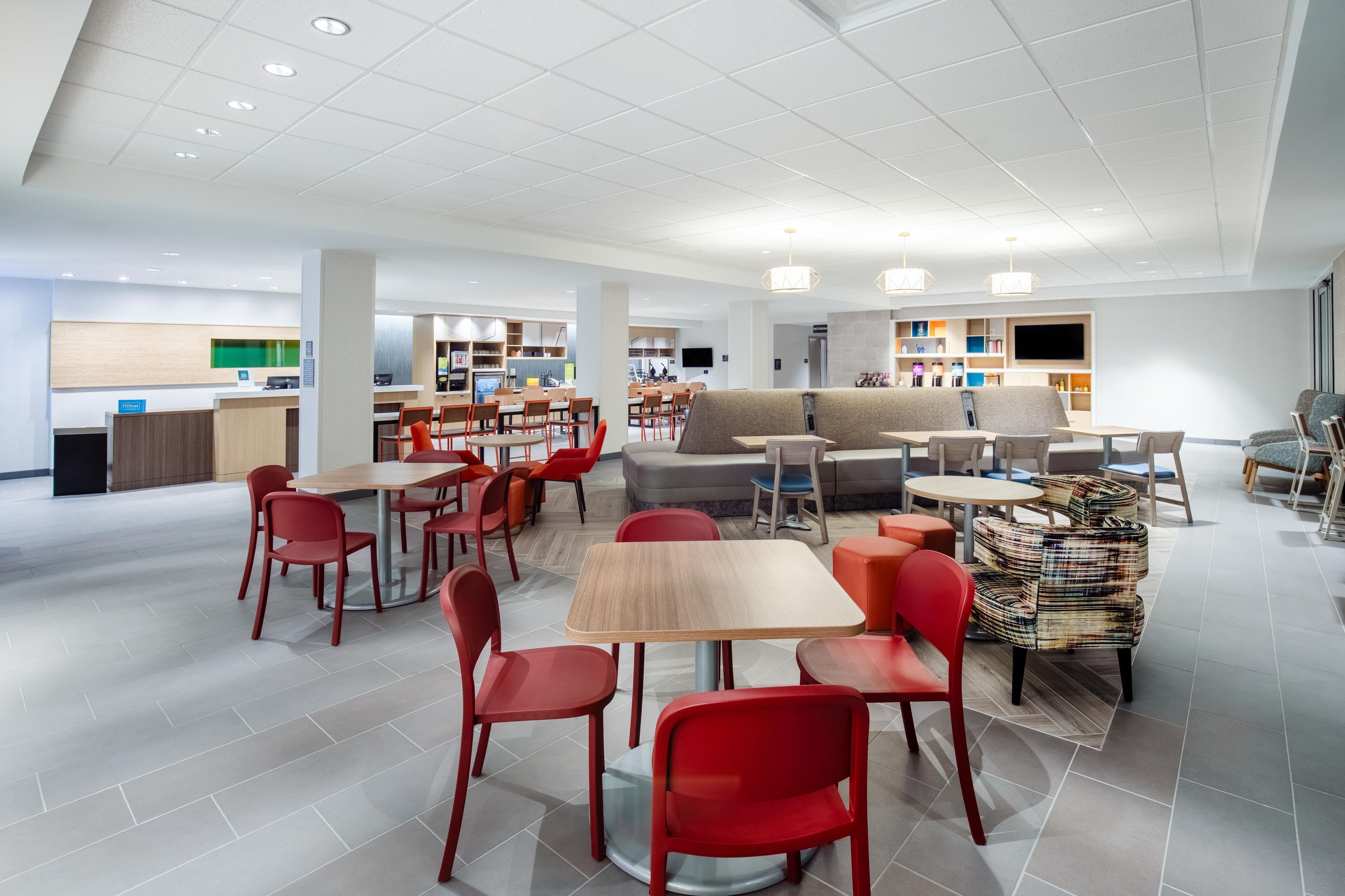 Un hall d’hôtel moderne comprenant un espace salon, un comptoir d’accueil et un espace de jeux pour enfants.