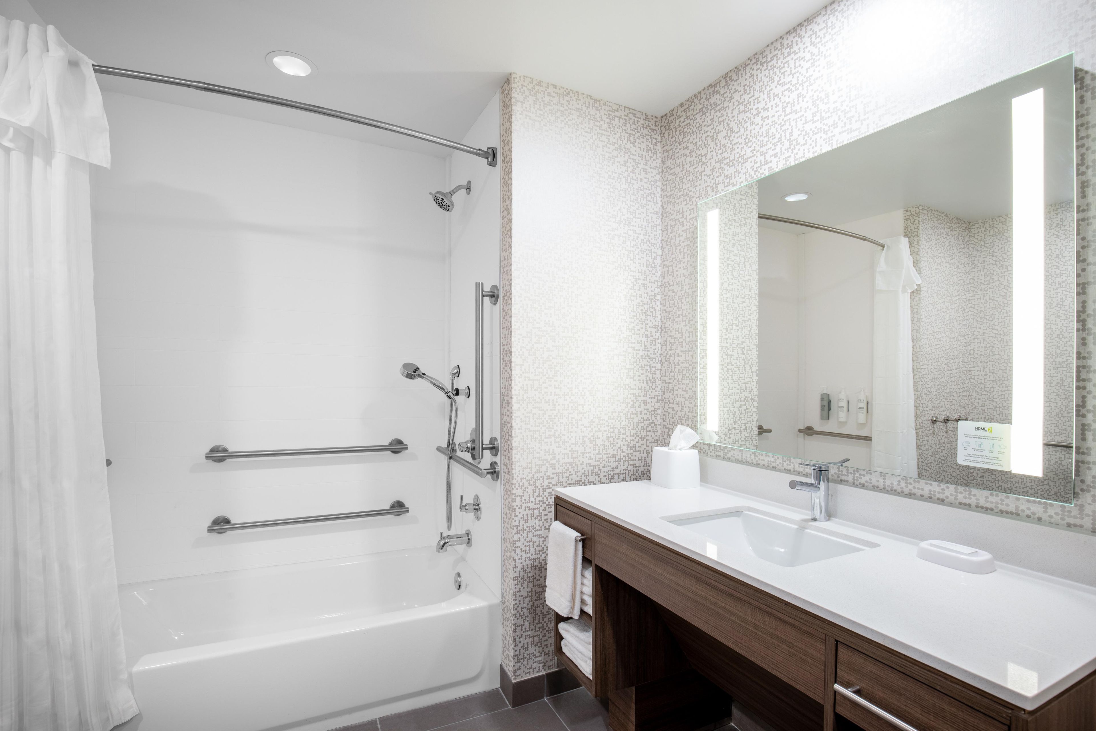 Un bagno moderno con doccia a filo pavimento, un mobile lavabo con specchio e una vasca da bagno.