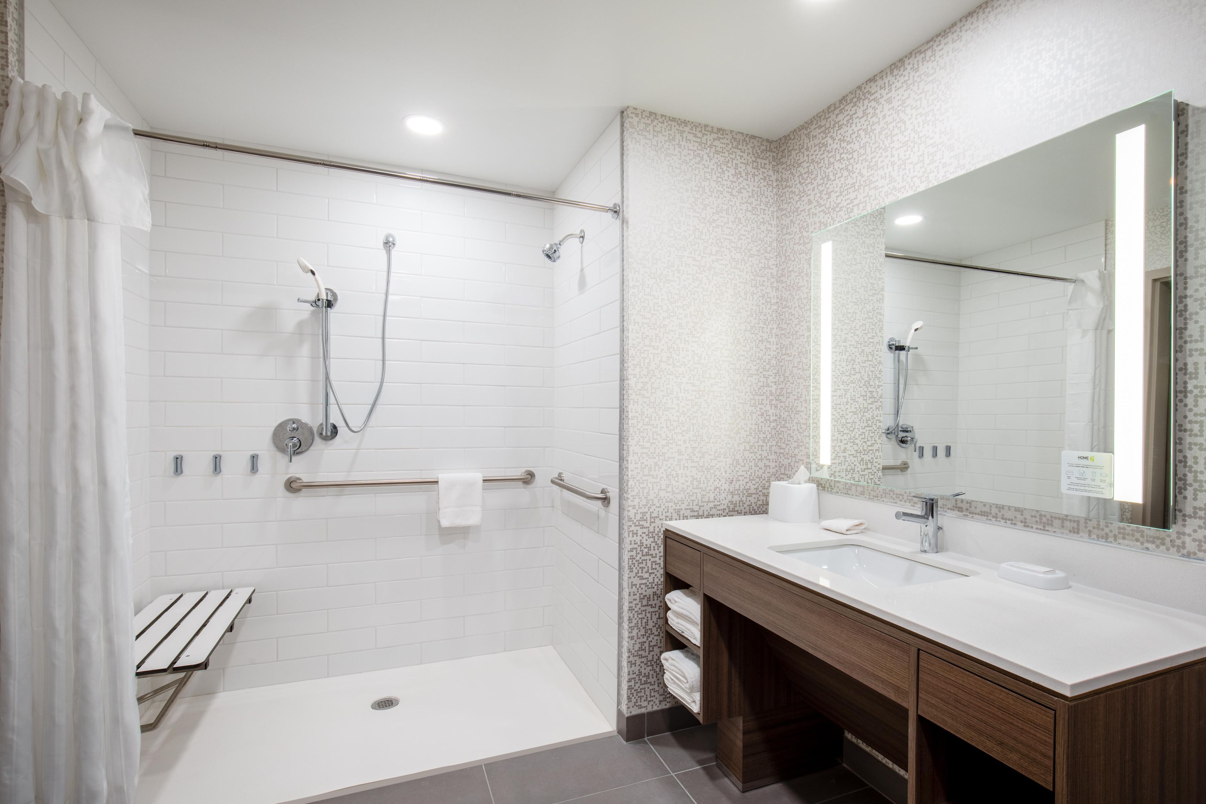Un baño moderno con cabina de ducha a ras de suelo, tocador con espejo y retrete.