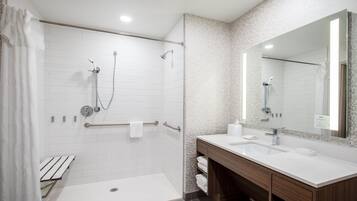 Un baño moderno con cabina de ducha a ras de suelo, tocador con espejo y retrete.