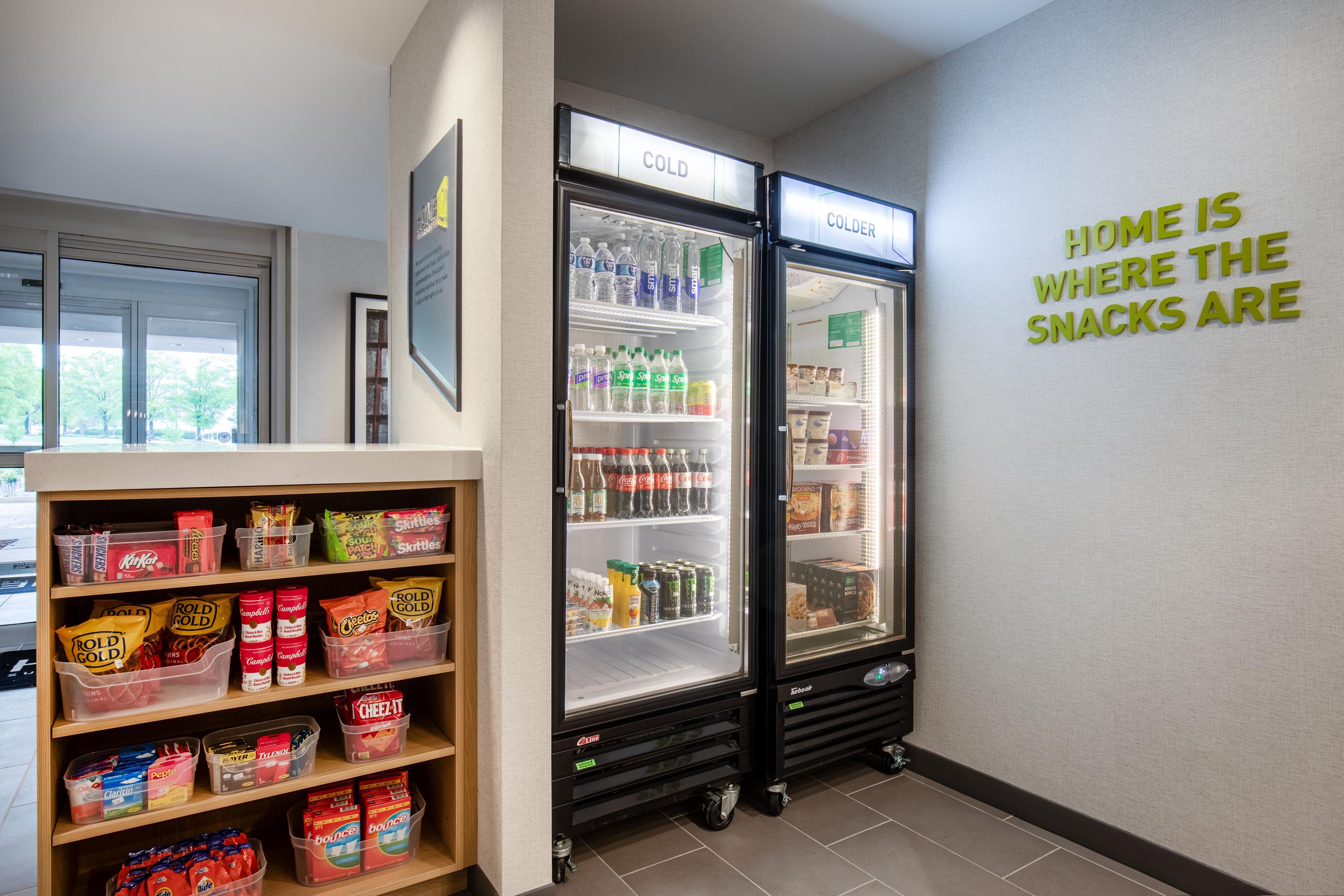 Zona de venta de snacks con un congelador y estanterías llenas de productos y bebidas.