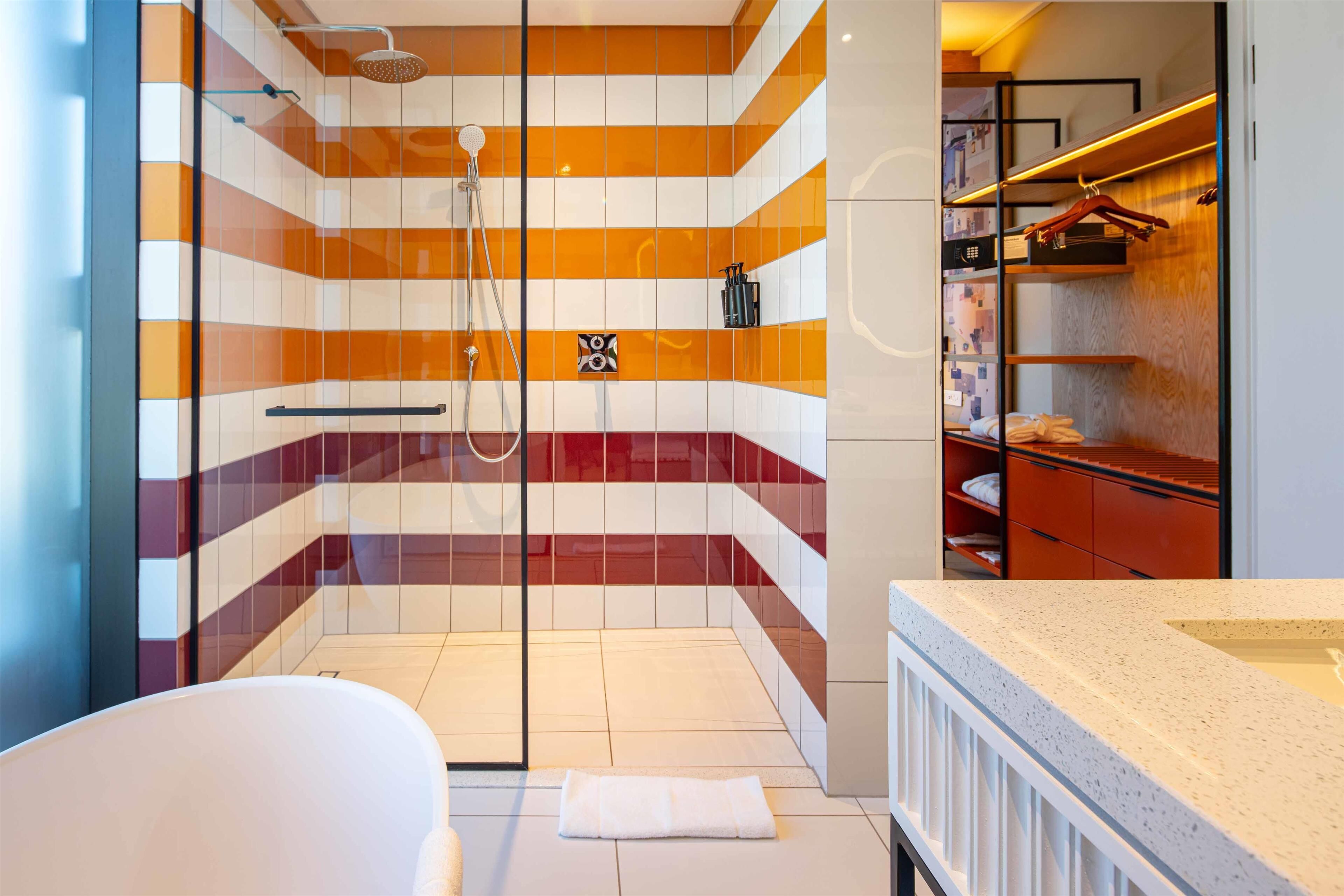 Une salle de bain moderne avec une douche à l’italienne en verre, une baignoire blanche et un meuble-lavabo en bois avec un miroir.