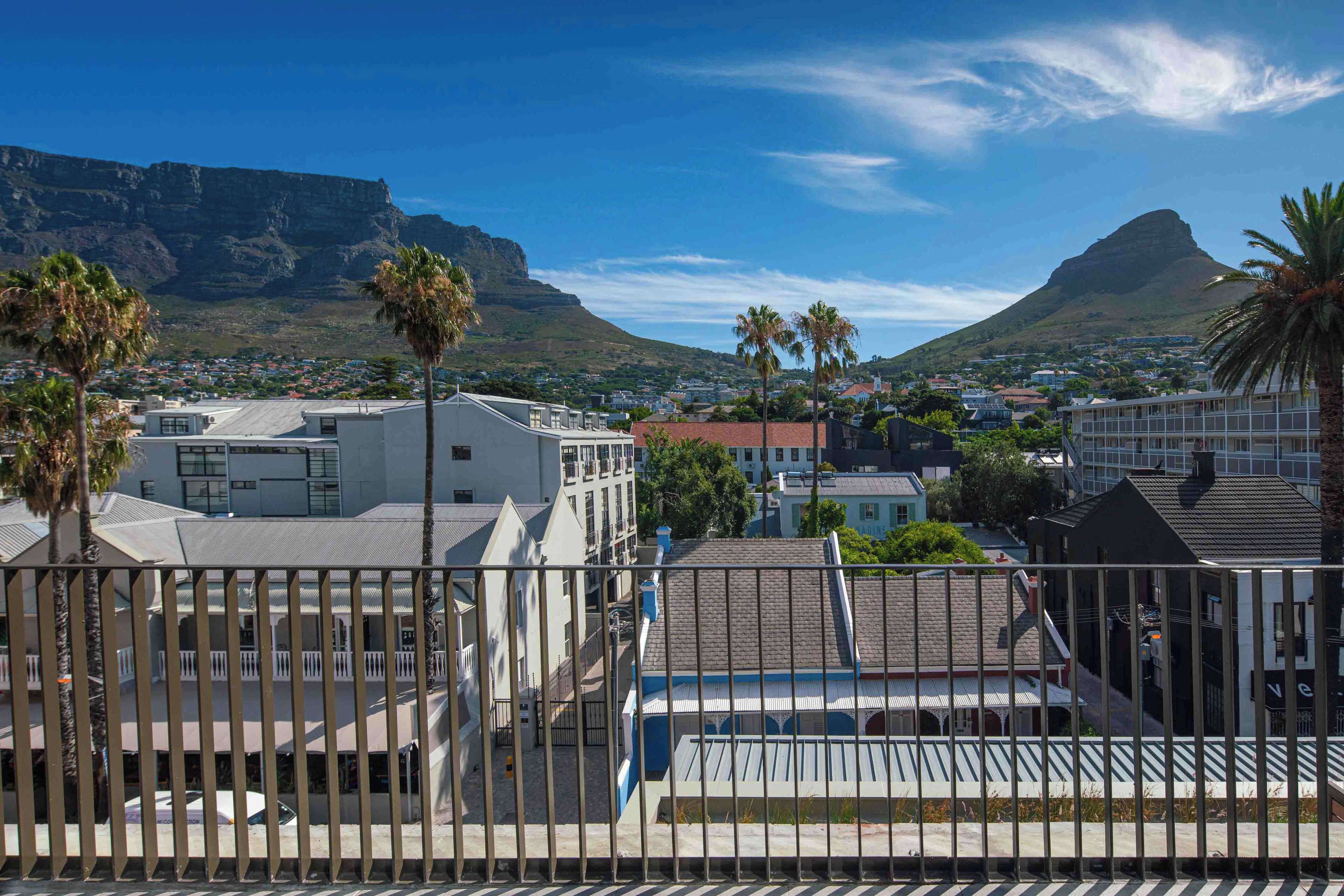 A residential area with buildings, palm trees, and mountains in the background.