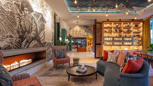 Un espacio de sala acogedor con chimenea, asientos cómodos y una estantería llena de libros.
