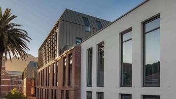 A modern building with a mix of brick and white facades, large windows, and a sloped roof.