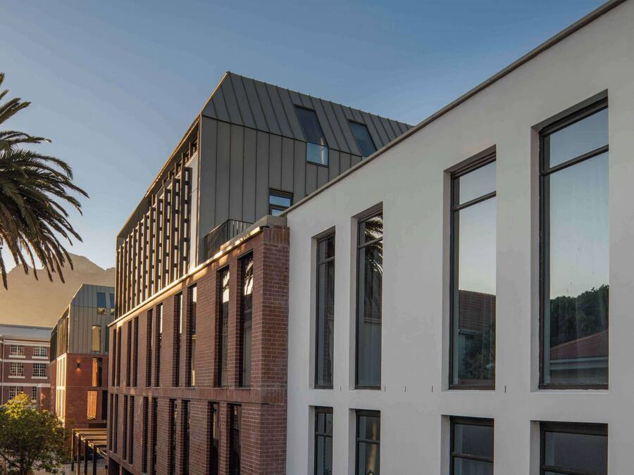 A modern building with a mix of brick and white facades, large windows, and a sloped roof.