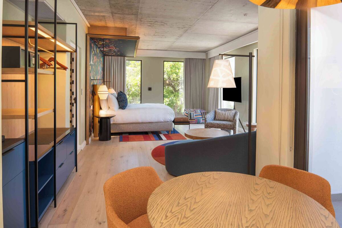 Una habitación de hotel moderna con cama, sofá, mesa de comedor y televisor.