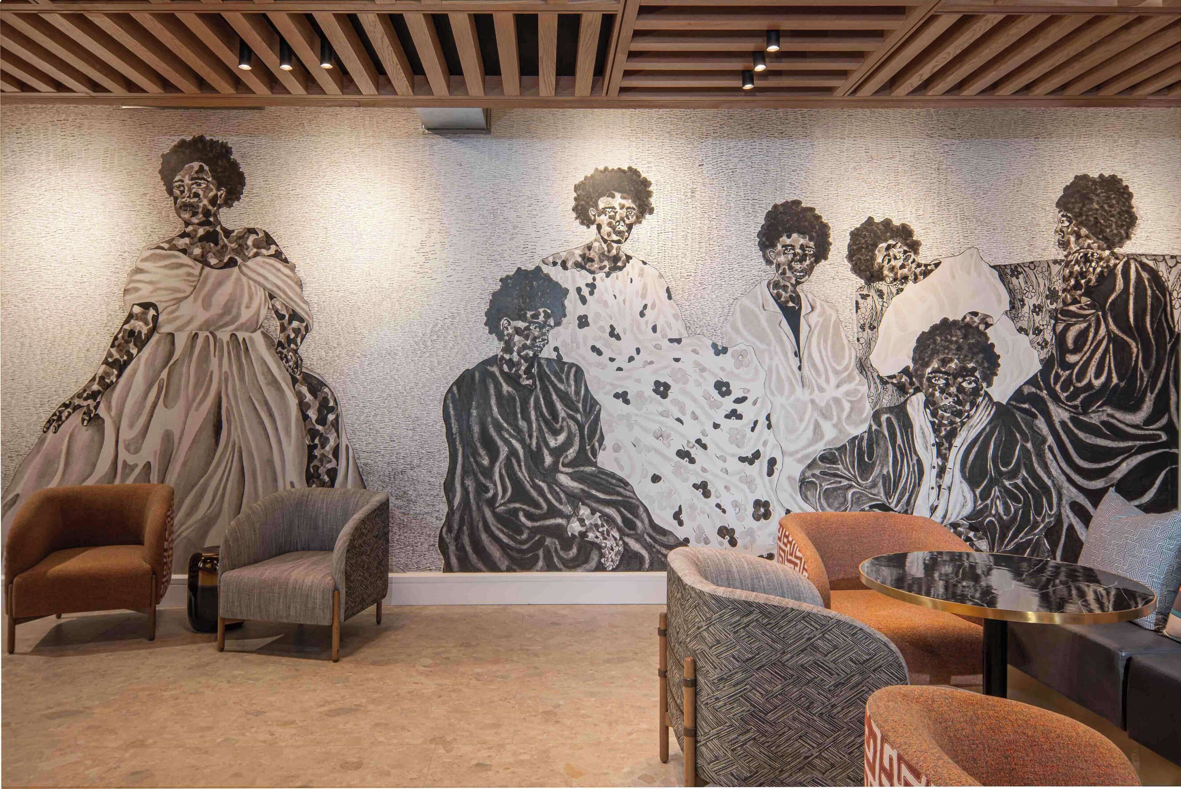 A room with a large mural on the wall, a round table, and several chairs.